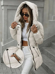 Woman wearing a white puffer jacket and white pants on a city street.
