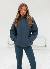 Woman wearing a blue hoodie and leggings against a white background