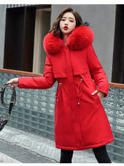 Woman wearing a red coat with a fur-lined hood on a city street.