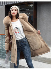 Woman wearing a long beige coat with a fur-lined hood on a city street.