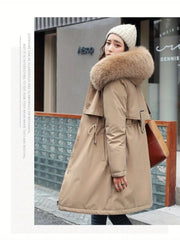 Woman wearing a beige winter coat with a fur-lined hood in an urban setting.