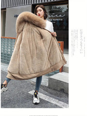 Woman wearing a long beige coat with a fur hood on a city street.