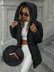 Woman wearing a black puffer jacket and white pants, standing on steps.