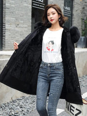 Woman wearing a black coat, white t-shirt with graphic design, and blue jeans outdoors.