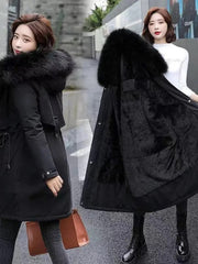 Two women wearing black winter coats with large fur hoods on a city street.