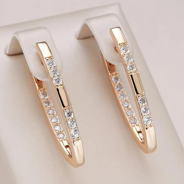 Rose gold hoop earrings with embedded diamonds on a light beige background