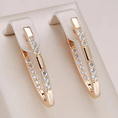 Rose gold hoop earrings with embedded diamonds on a light beige background