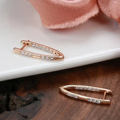 Rose gold earring with clear stones on a white and wooden surface