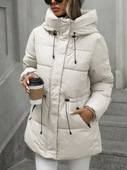 Person wearing a white puffer coat holding a coffee cup against a gray background
